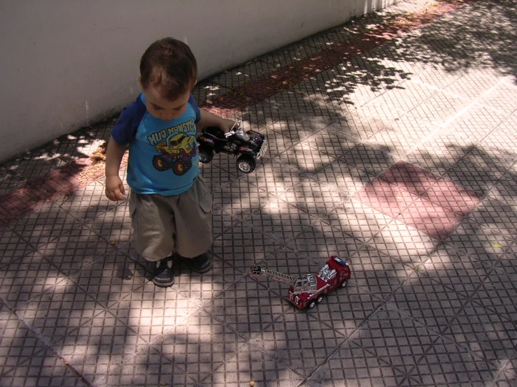 a little boy standing next to a toy car