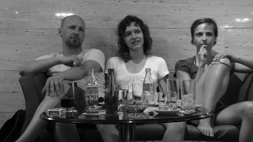 a group of people sitting at a table with bottles