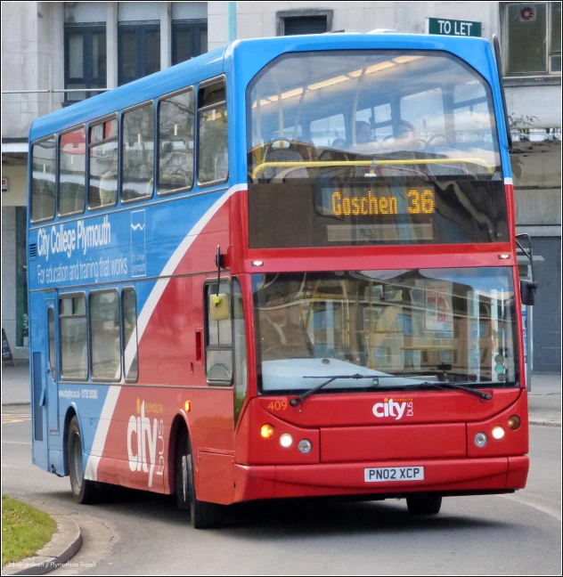 a blue, red and white double decker bus on roadway