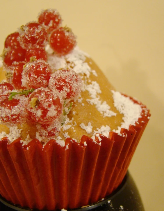 this cupcake has sprinkles of powder and cherry topping on top