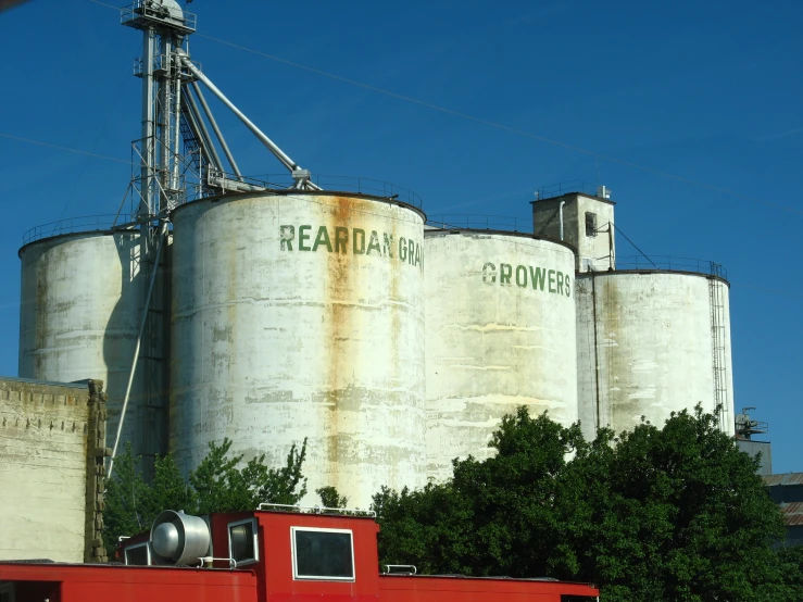 an old red tractor and grain elevator against a blue sky