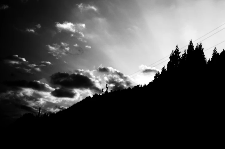 a black and white image with a power line on a dark hillside