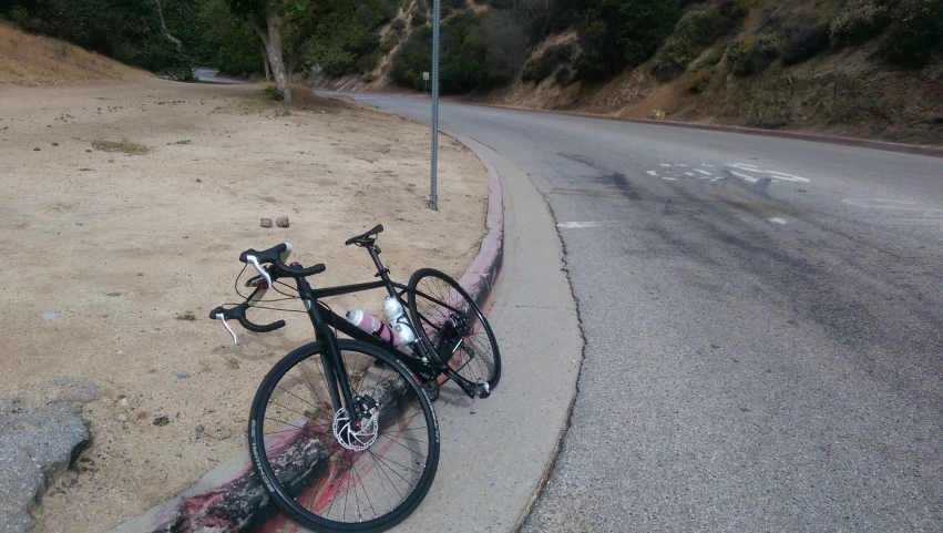 a bike leans against a curb by a street