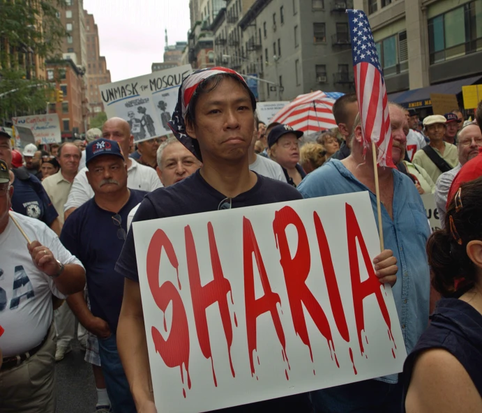 a protester holds up a sign with the word, sharia