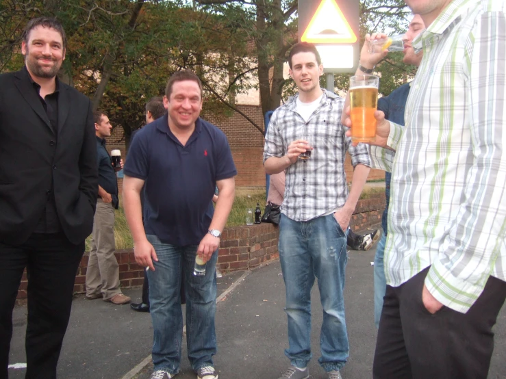 men standing outside, holding beers in hand