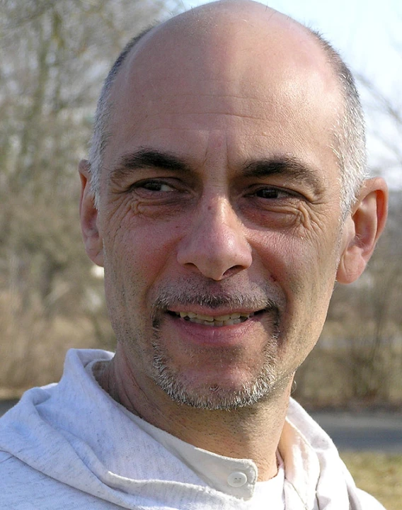 an older man in a white shirt smiling at the camera