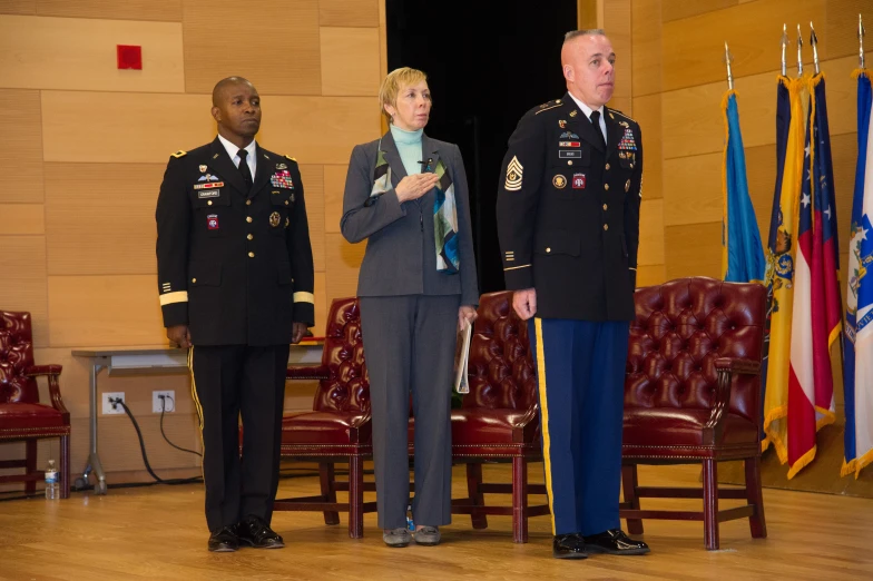 three men in military uniforms stand in front of flags