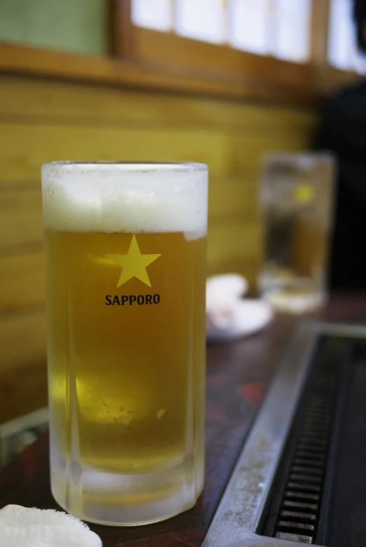 a glass of beer with a golden star logo sitting on a table