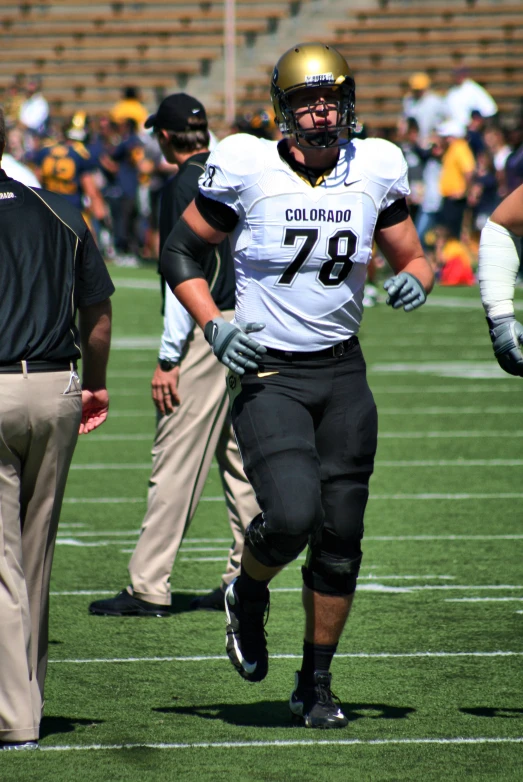 football player running across the field with several officials nearby