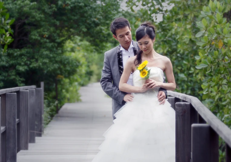 the bride is holding a sunflower next to a man who's holding a white bouquet