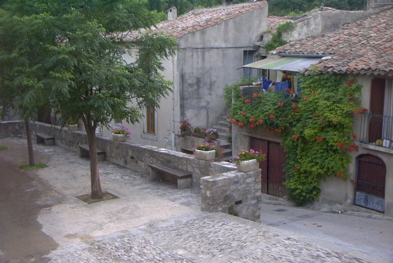 an old stone building with flowers growing on it's roof