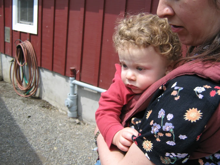 a small child held by a woman who is holding a baby