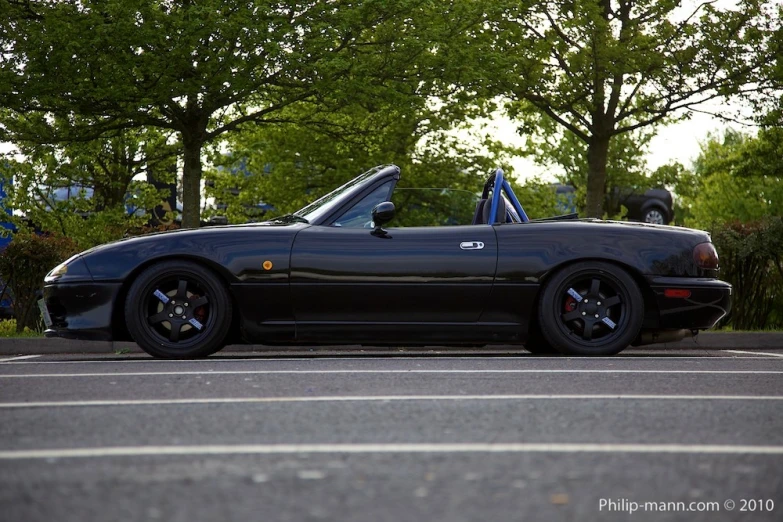 the black sports car has its hood up and is parked in the middle of the road