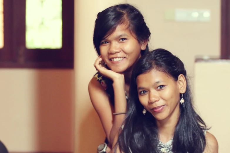 two young women pose for the camera in a room