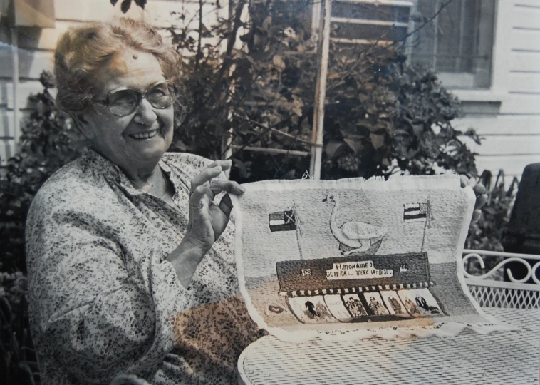 an older woman holding up a picture of a house