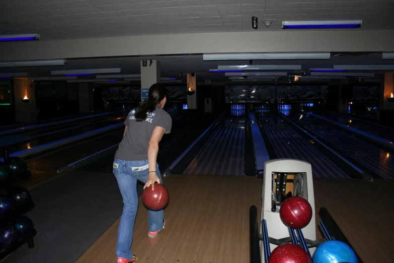 woman walking down the bowling alley carrying two bowling balls