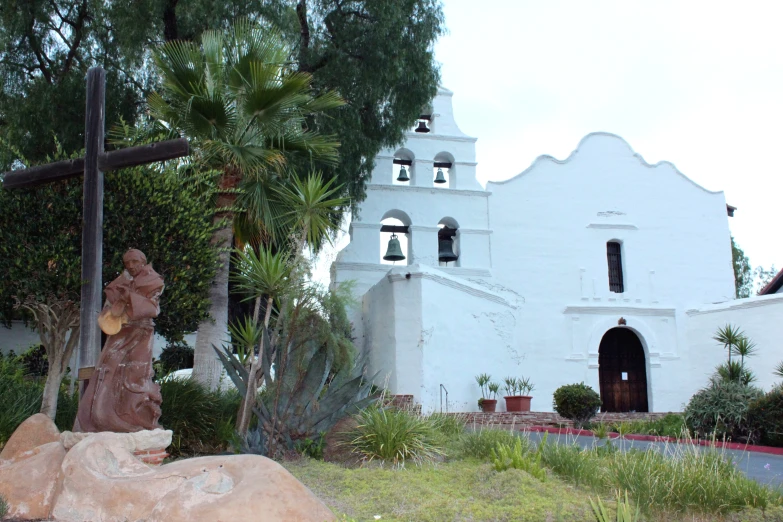 a very large church with plants and a cross next to it