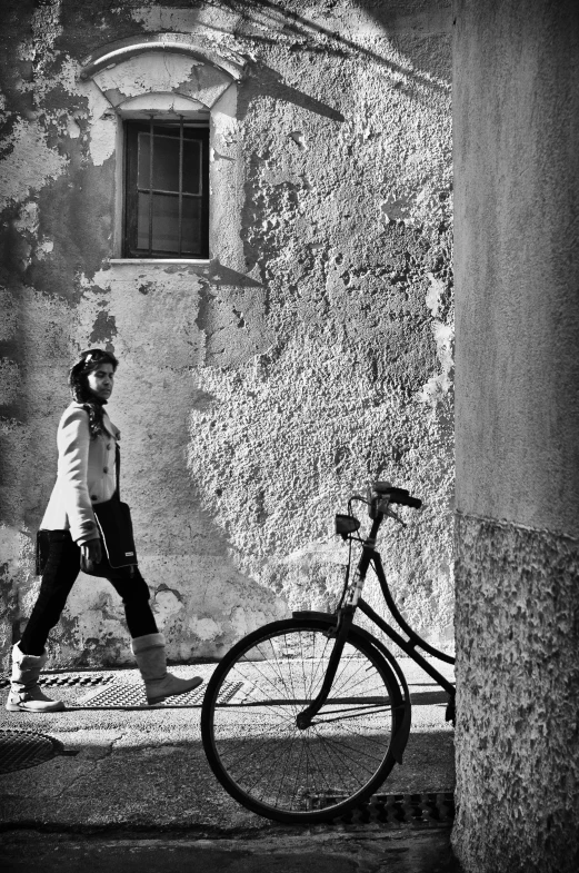 a young woman walking down the sidewalk in front of a bike