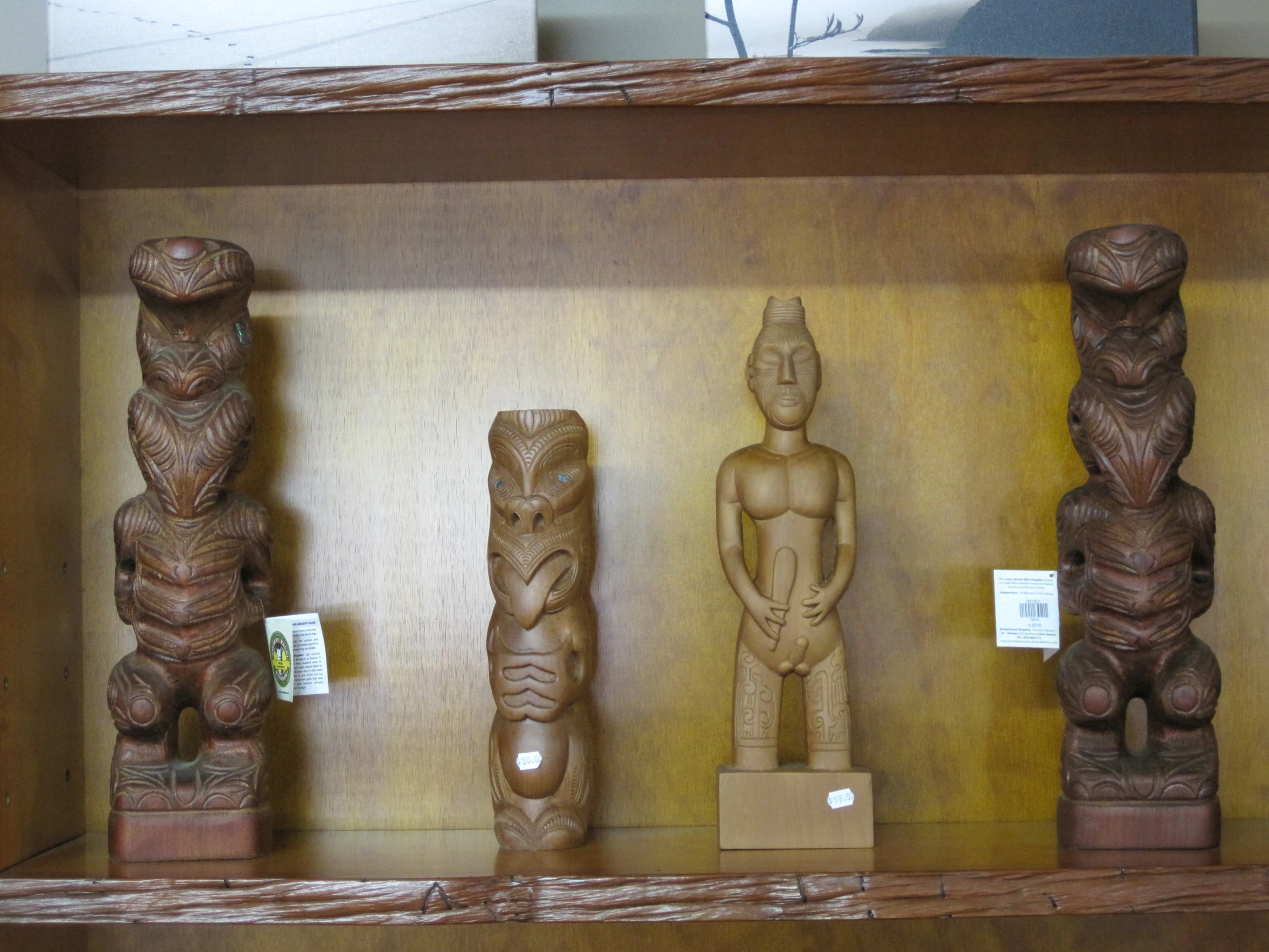 some wooden carving statues are lined up on the shelves