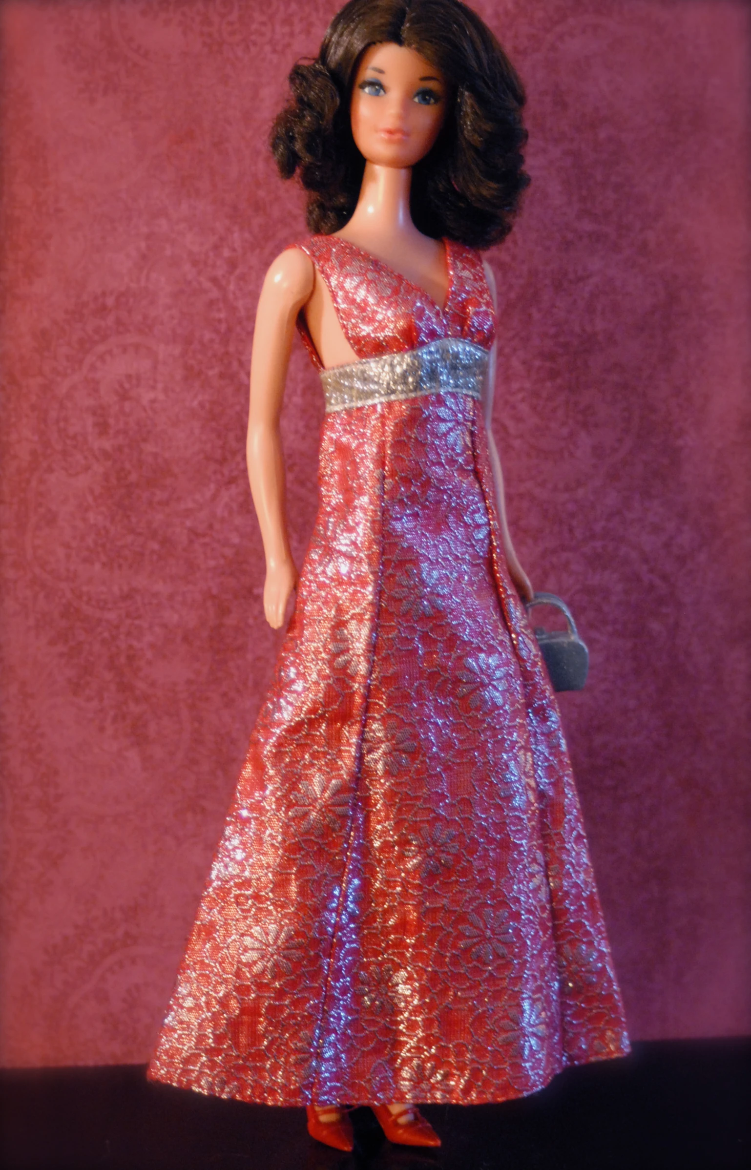 a doll dressed in a pink dress with a silver purse