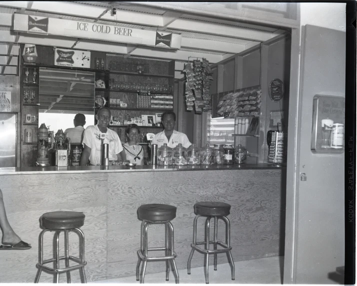 two women standing in front of a counter and some stools