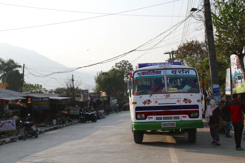 a city bus parked at an intersection with people crossing