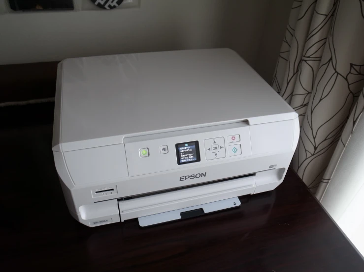 a white printer sitting on top of a wooden desk