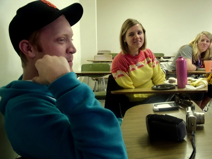 a man looks off into the distance while sitting in class with friends