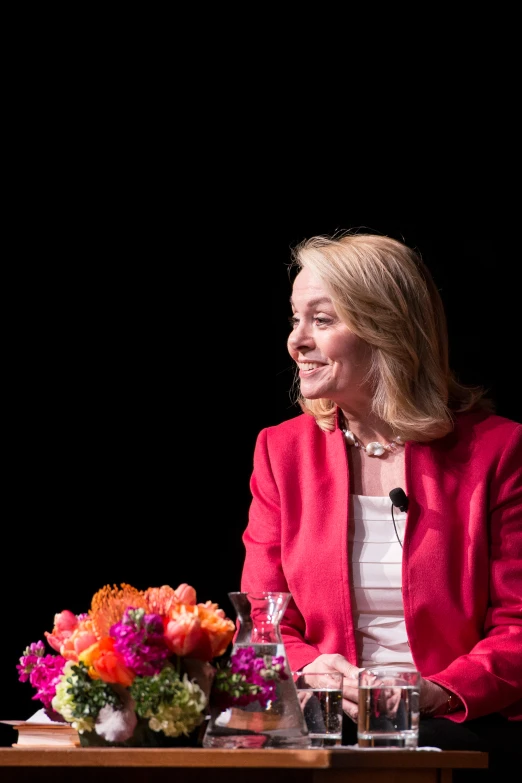 a woman sitting at a table with a bouquet on the side of it