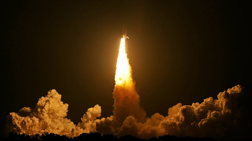 a rocket with clouds is lit by light from the back