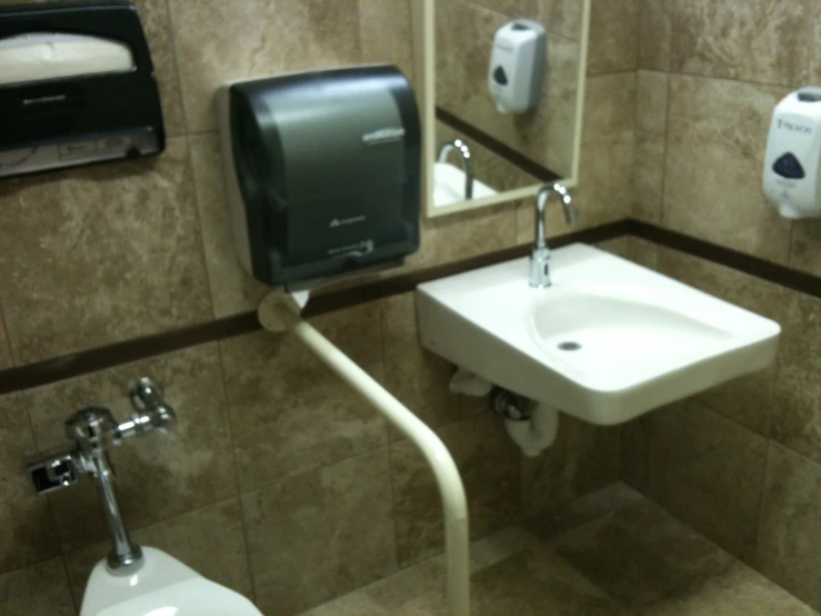 a toilet, urinal and hand dryer in a bathroom