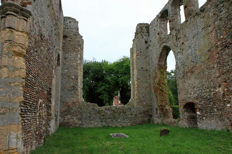 a stone building with arches at the end and grass at the base