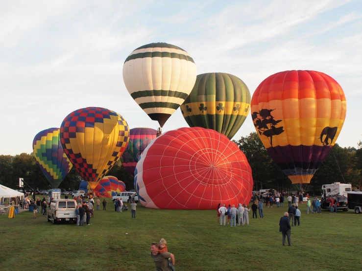 a group of people standing next to several  air balloons