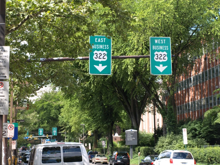 a street filled with traffic underneath tall green trees