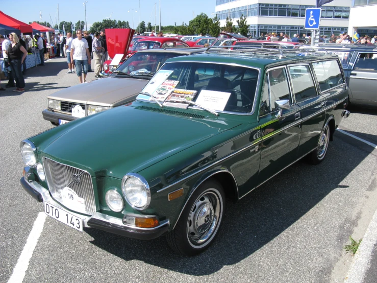 an old green car sitting in a parking lot