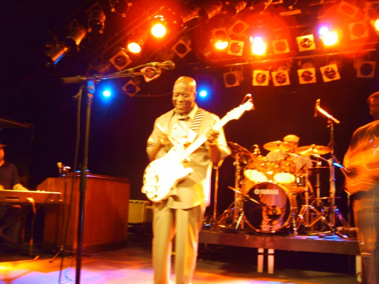 a man on stage playing guitar while another plays the bass