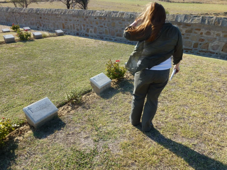 a woman is looking at the ground of a gravestone