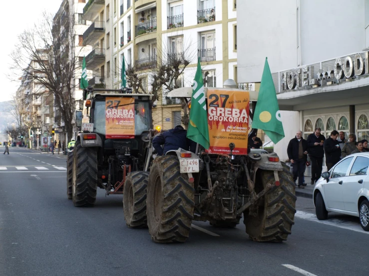 two tractors with flags are on a street