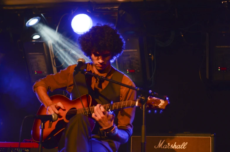 a man with black hair playing an acoustic guitar