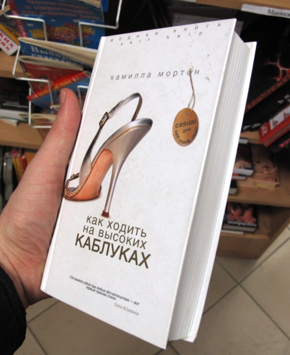 a woman holding up a book in front of a shelf full of books