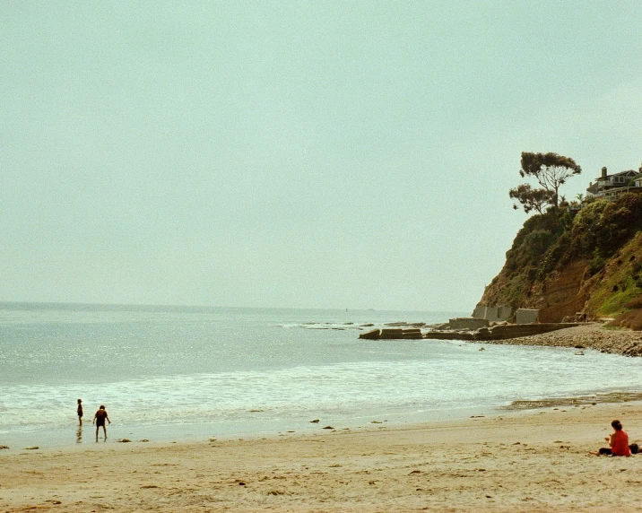 a couple walking on a beach near the ocean