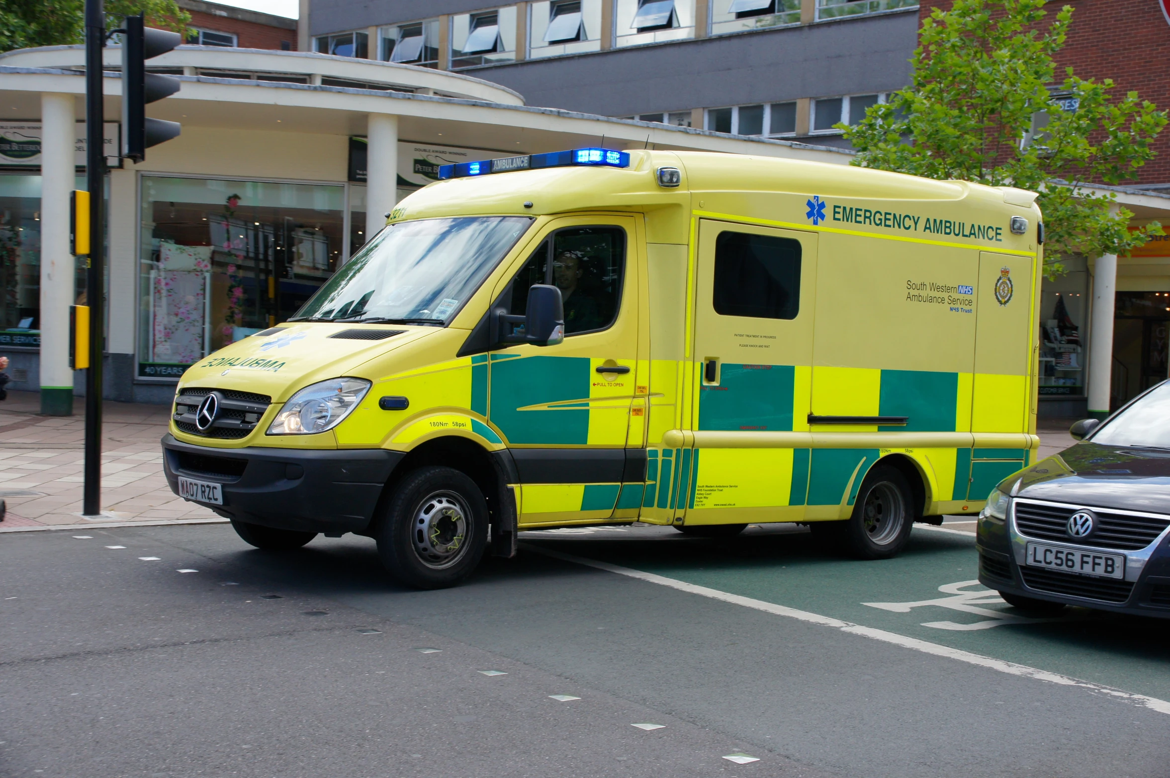 an ambulance drives down the road in front of buildings