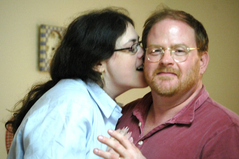 a man with glasses kissing a woman who is wearing glasses