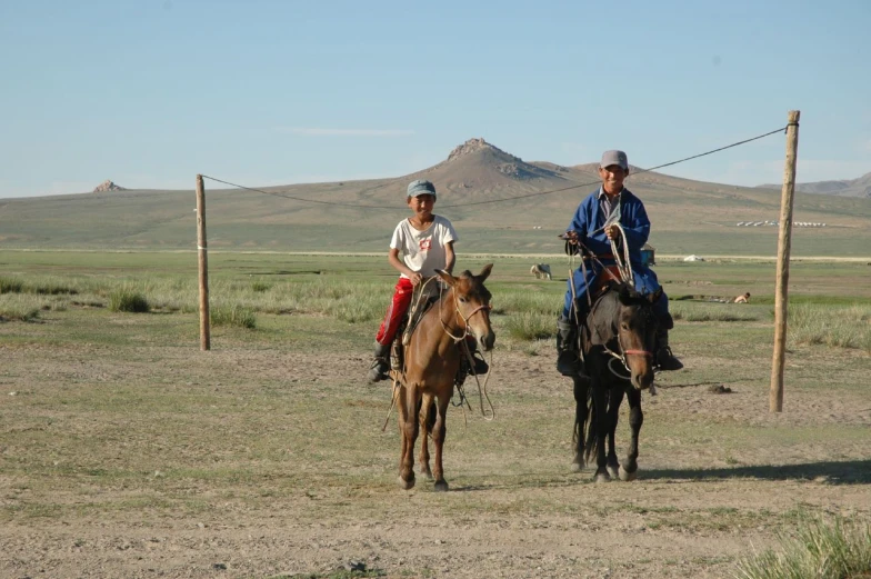 two people ride horses with mountains in the background