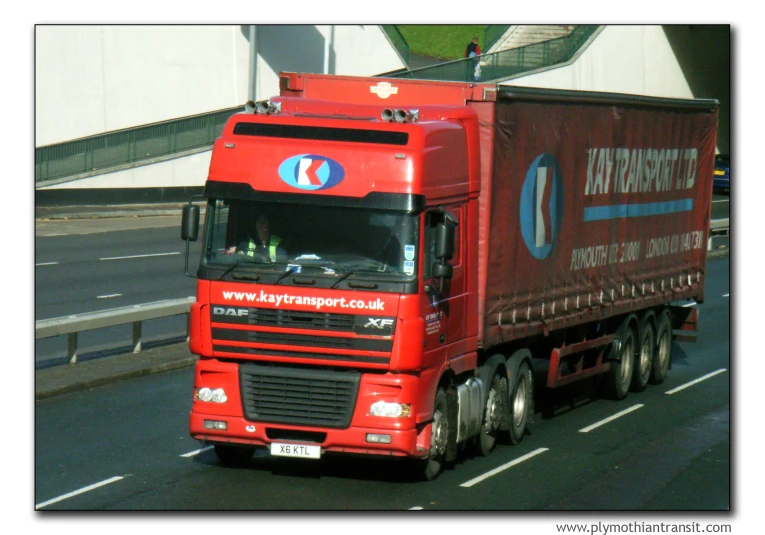 a red transport truck is driving down the road