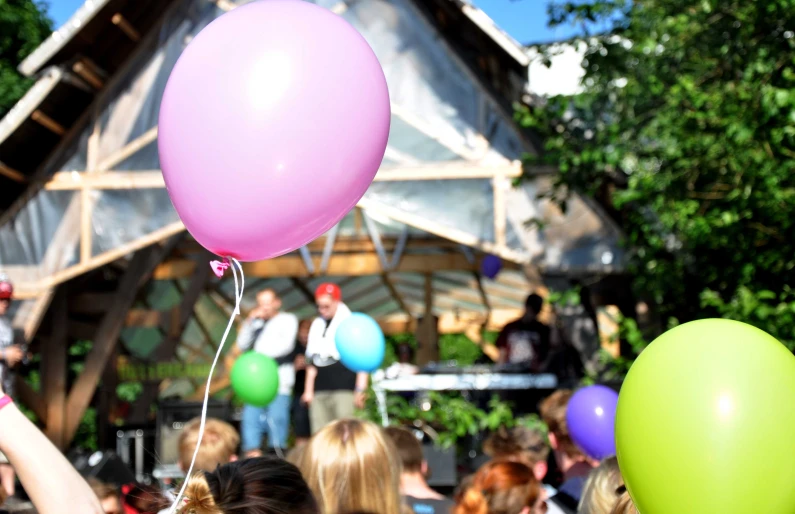 a crowd of people holding balloons in front of a building