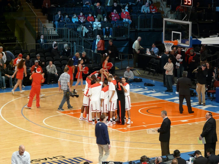 a group of players with arms up at a basketball game