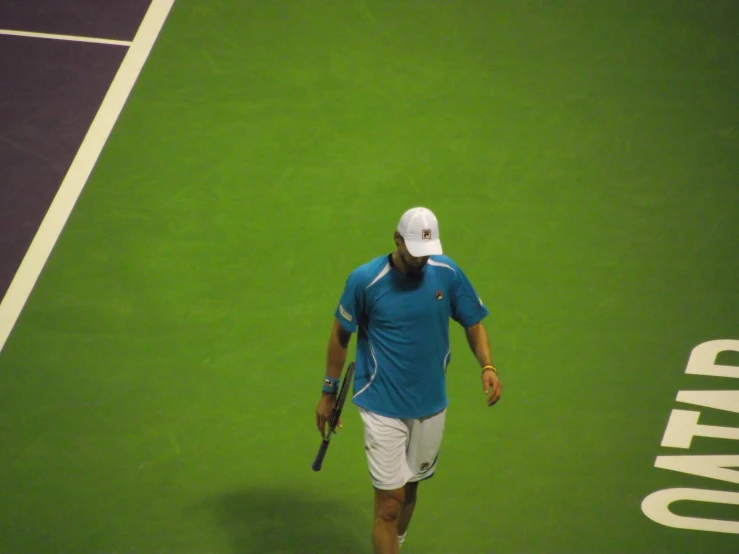 the tennis player has a blue shirt and white hat