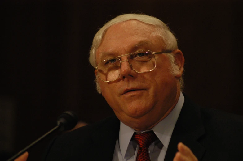 an older man wearing a red tie and glasses