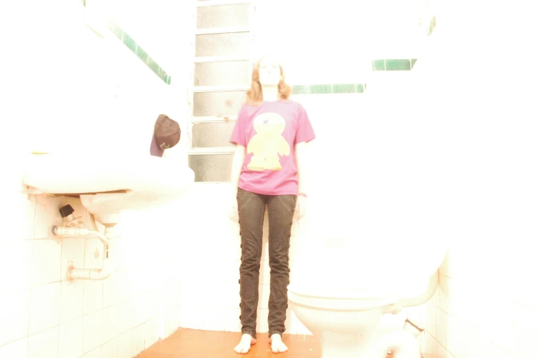 a young lady standing in a bathroom with a sink and toilet